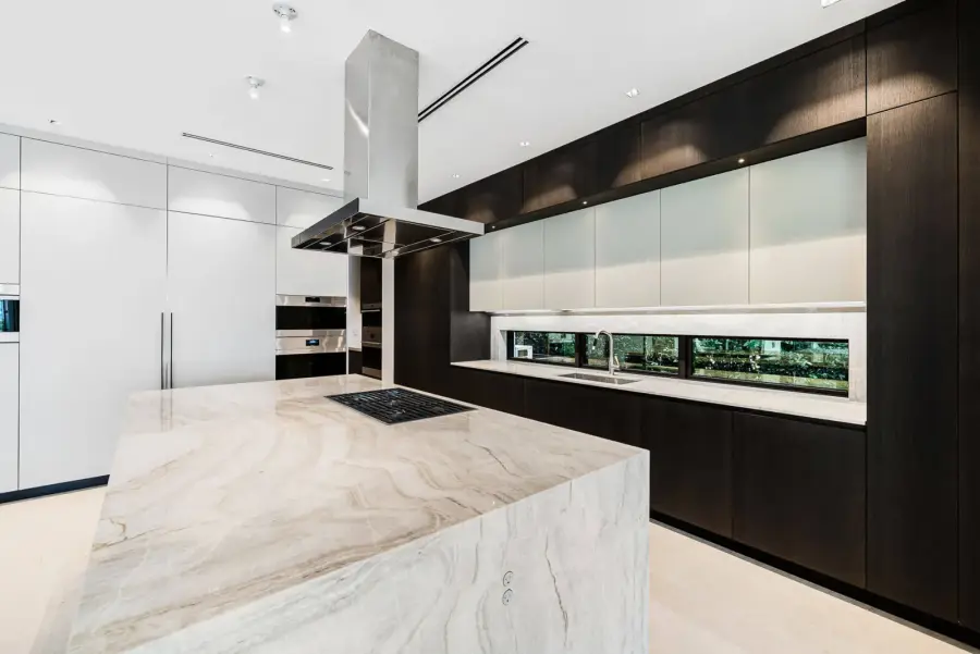 Kitchen with a waterfall stone island and dark wood cabinetry