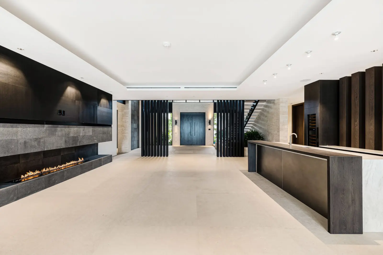 Living room with a linear fireplace and a dark wood bar island