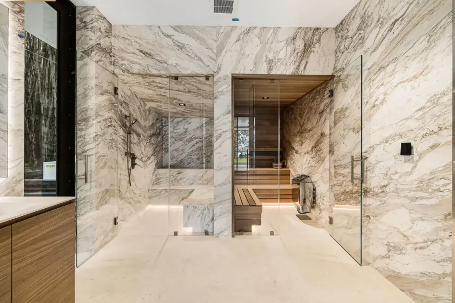 Marble steam shower beside a wood-lined sauna